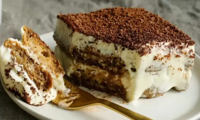 Un morceau de tiramisu, dessert aux origines italiennes, avec ses couches de biscuits imbibés et de crème onctueuse, saupoudré de cacao.