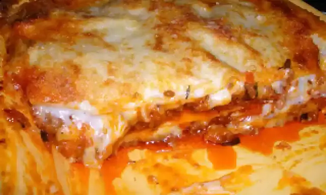Une part généreuse de lasagne à la viande hachée, avec sa couche de fromage gratiné et sa sauce tomate débordante. Un délice réconfortant.
