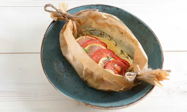 Poisson cuit en papillote avec tomates et citron, une recette bar simple et savoureuse.