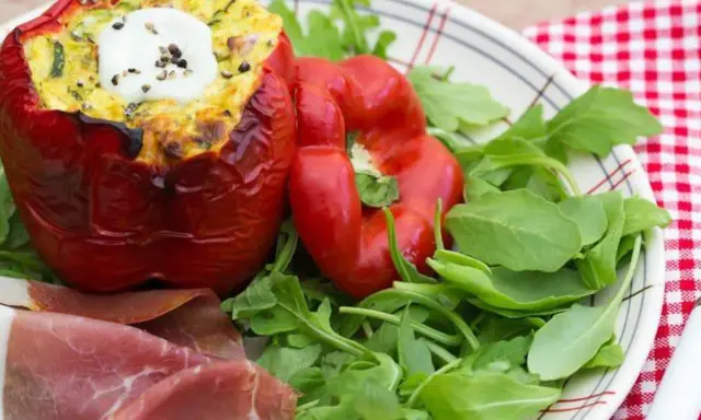 Poivrons farcis à l'italienne, garnis d'une préparation savoureuse et surmontés d'une touche de crème fraîche. Servi avec roquette et fines tranches de jambon.