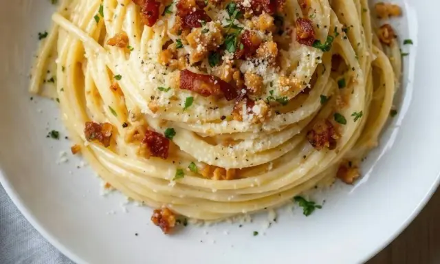 Un plat de pâtes carbonara végétariennes, garni de chapelure croustillante et de persil frais.