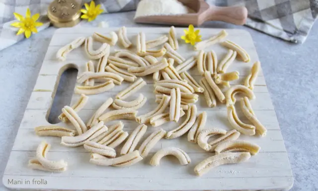 Des pâtes fraîches, prêtes à être cuites. Un aperçu de comment faire des pâtes maison, avec un rouleau à pâtes et de la farine.