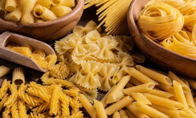 Assortiment de pâtes italiennes : fusilli, farfalle, penne, rigatoni et spaghetti, évoquant la qualité de la farine pour pâtes italiennes.