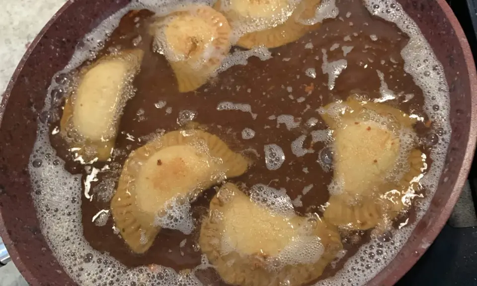 Des samboussek au fromage dorent dans l'huile chaude, formant des bulles joyeuses.