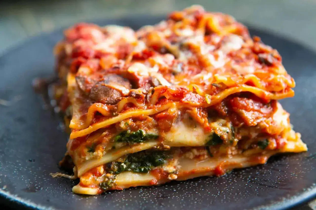 Une part g&eacute;n&eacute;reuse de lasagne v&eacute;g&eacute;tarienne, avec ses couches de p&acirc;tes, de sauce tomate, de fromage fondant et d'&eacute;pinards frais.