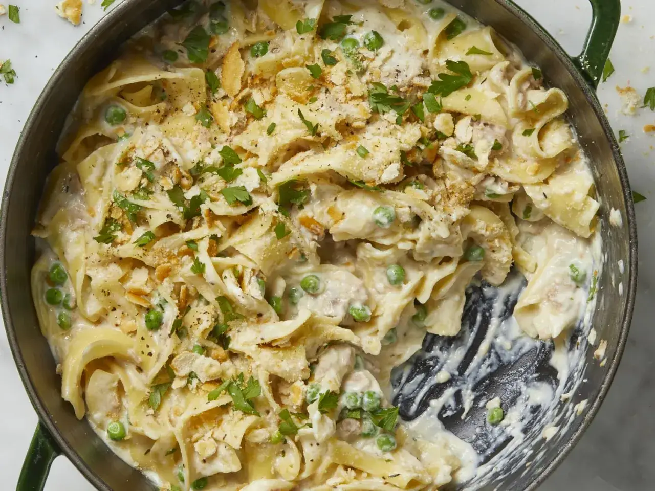 D&eacute;licieuse recette thon en boite avec des p&acirc;tes larges, petits pois et chapelure croustillante, garnie de persil frais.