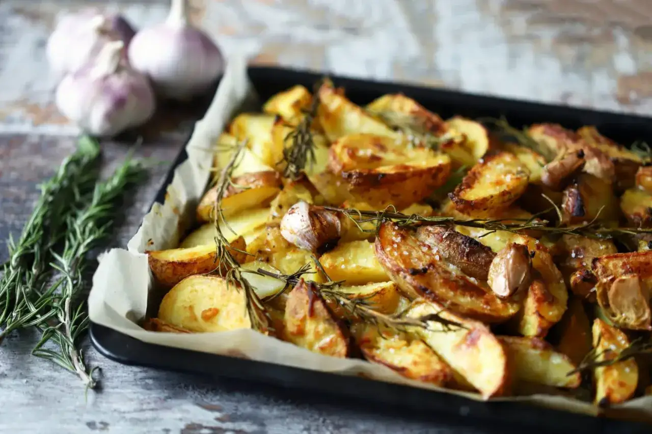 Pommes de terre au four dorées et croustillantes, parsemées de romarin frais et d'ail rôti. Un délice simple et savoureux.