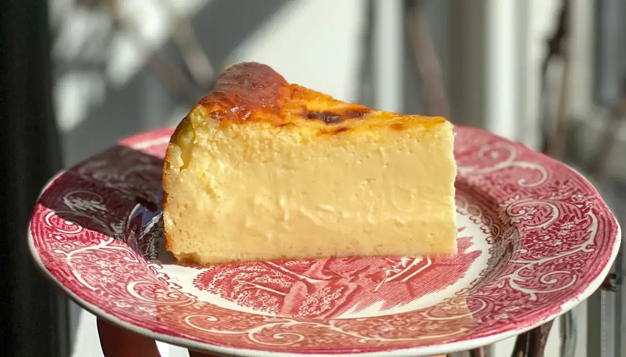 Tranche de cheesecake de San Sebastian, cr&eacute;meuse et dor&eacute;e, sur une assiette orn&eacute;e. Un d&eacute;lice &agrave; savourer.