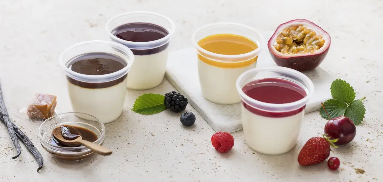 Quatre panna cotta individuelles garnies de coulis pour panna cotta : chocolat, fruits rouges, mangue et fruits de la passion. Fruits frais et vanille en garniture.