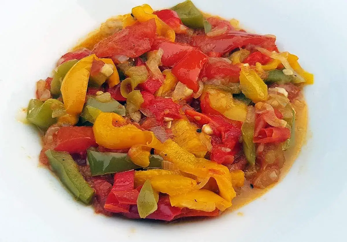 Une assiette de piperade recette, un plat color&eacute; de poivrons rouges, jaunes et verts mijot&eacute;s avec des tomates et des oignons.