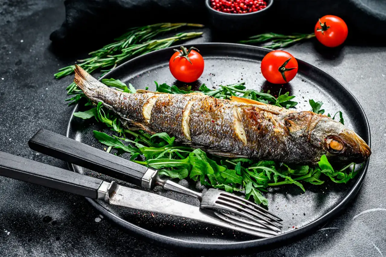 Un bar entier rôti sur un lit de roquette, garni de tomates cerises et de romarin. Une belle recette bar prête à être dégustée.