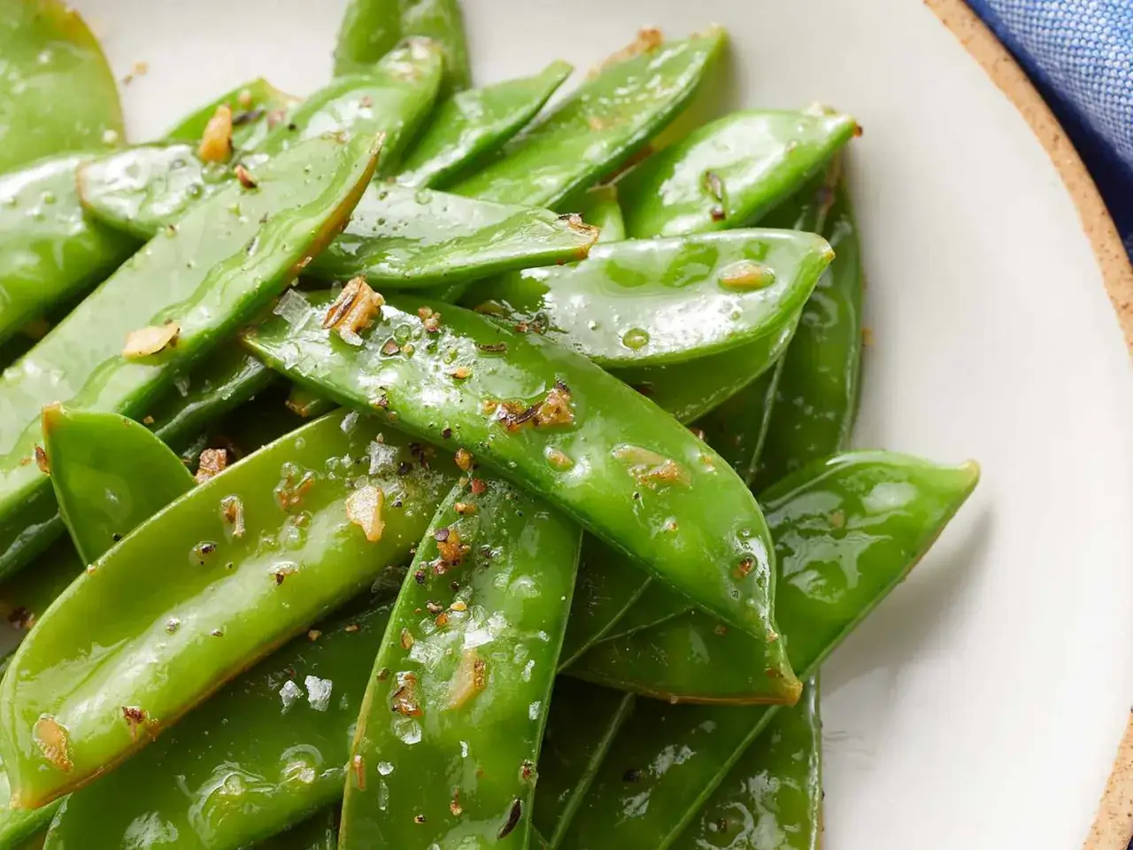 Pois gourmands brillants, assaisonnés de sel et de poivre, prêts pour la cuisson.