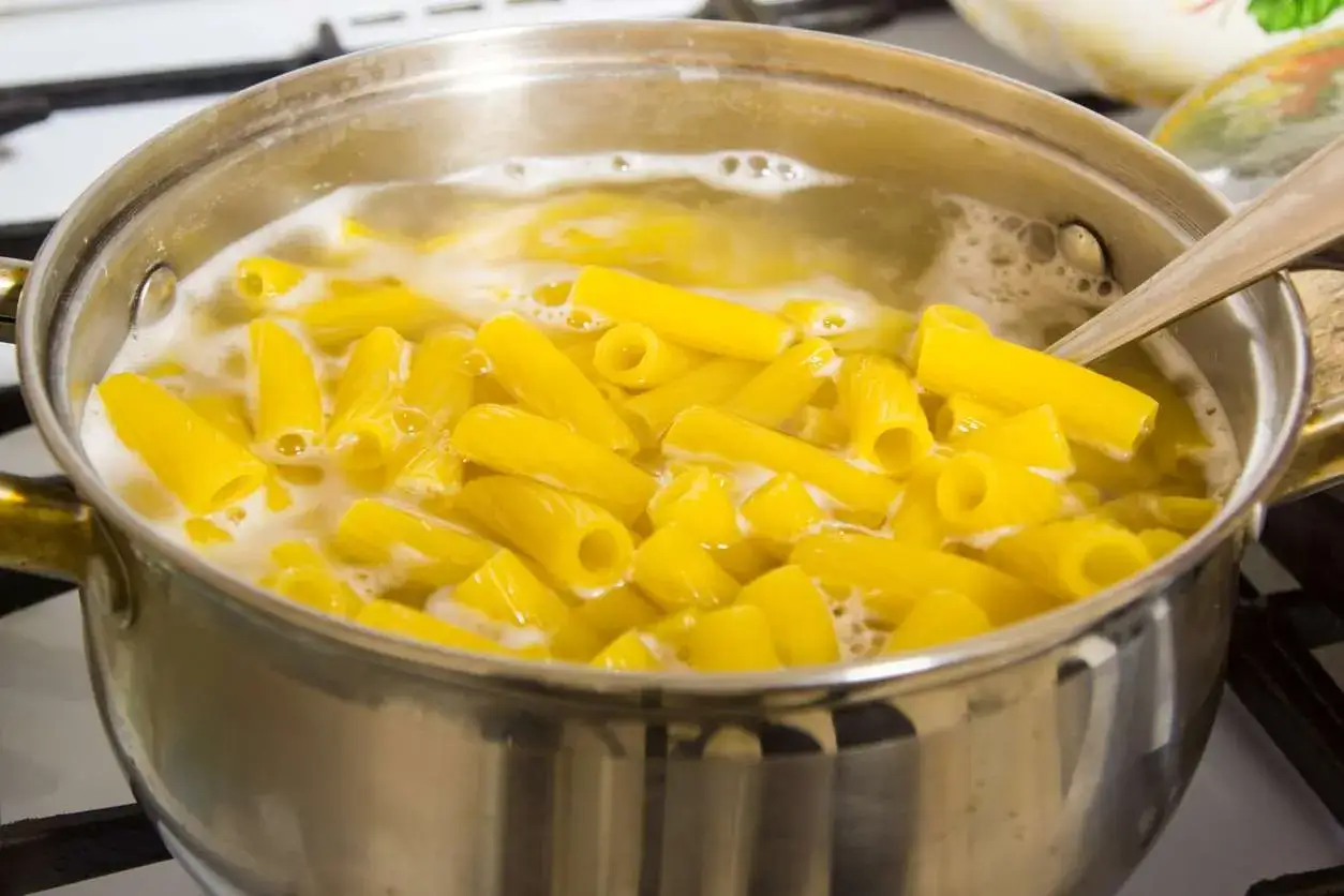 Pâtes rigatoni qui mijotent dans une casserole d'eau bouillante, prêtes pour un délicieux one pot pasta.