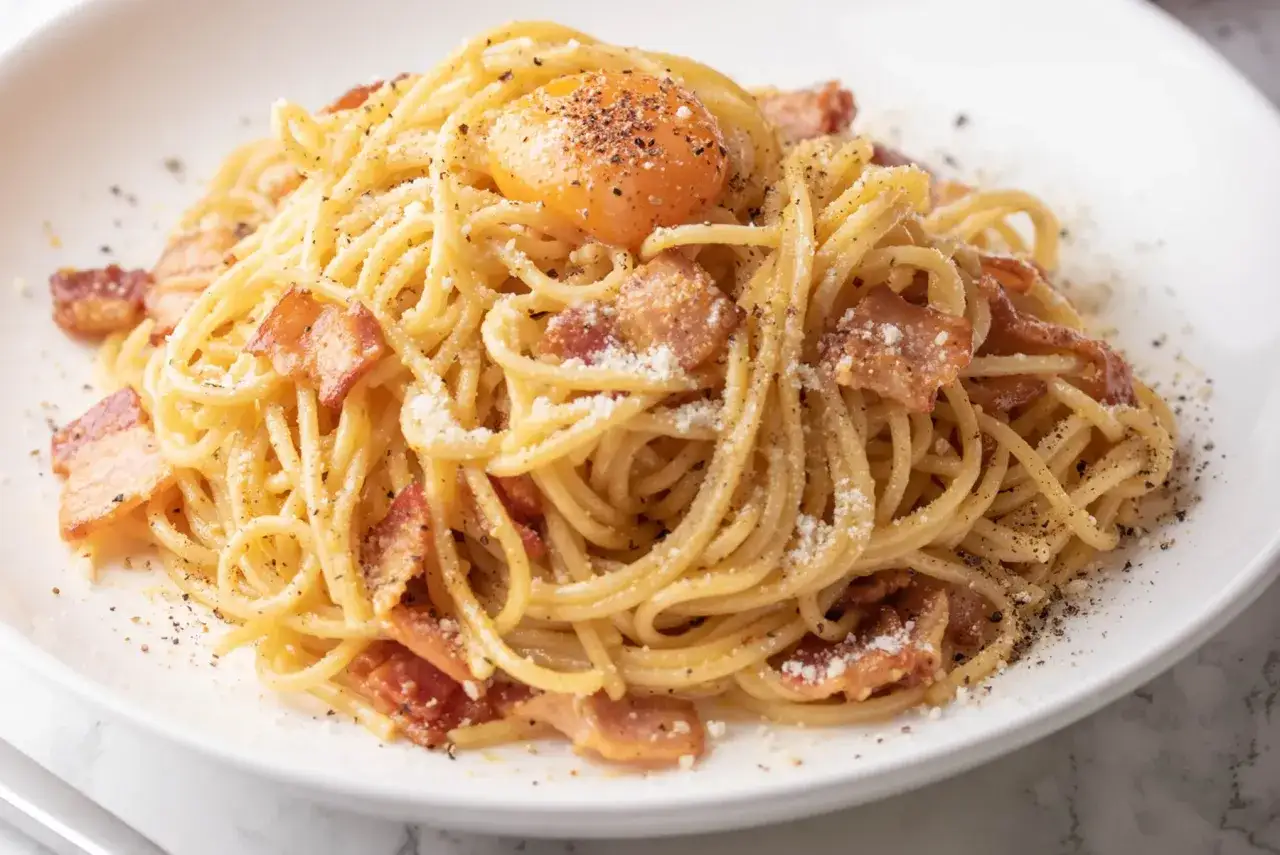 Un plat de spaghetti carbonara cr&eacute;meux, garni d'un jaune d'&oelig;uf, de lardons croustillants et de poivre noir. Les meilleures p&acirc;tes pour carbonara sont ici !