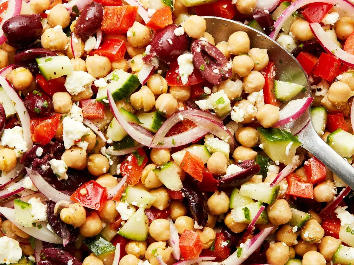 Salade colorée de pois chiches, concombre, poivron rouge, olives et feta. Parfait pour un repas léger, cette recette met en valeur la cuisson pois chiche.