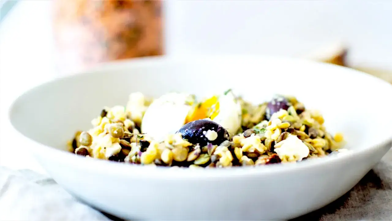 Salade de lentilles vertes avec œuf mollet, olives et feta. Un plat savoureux et sain, parfait pour un repas léger.