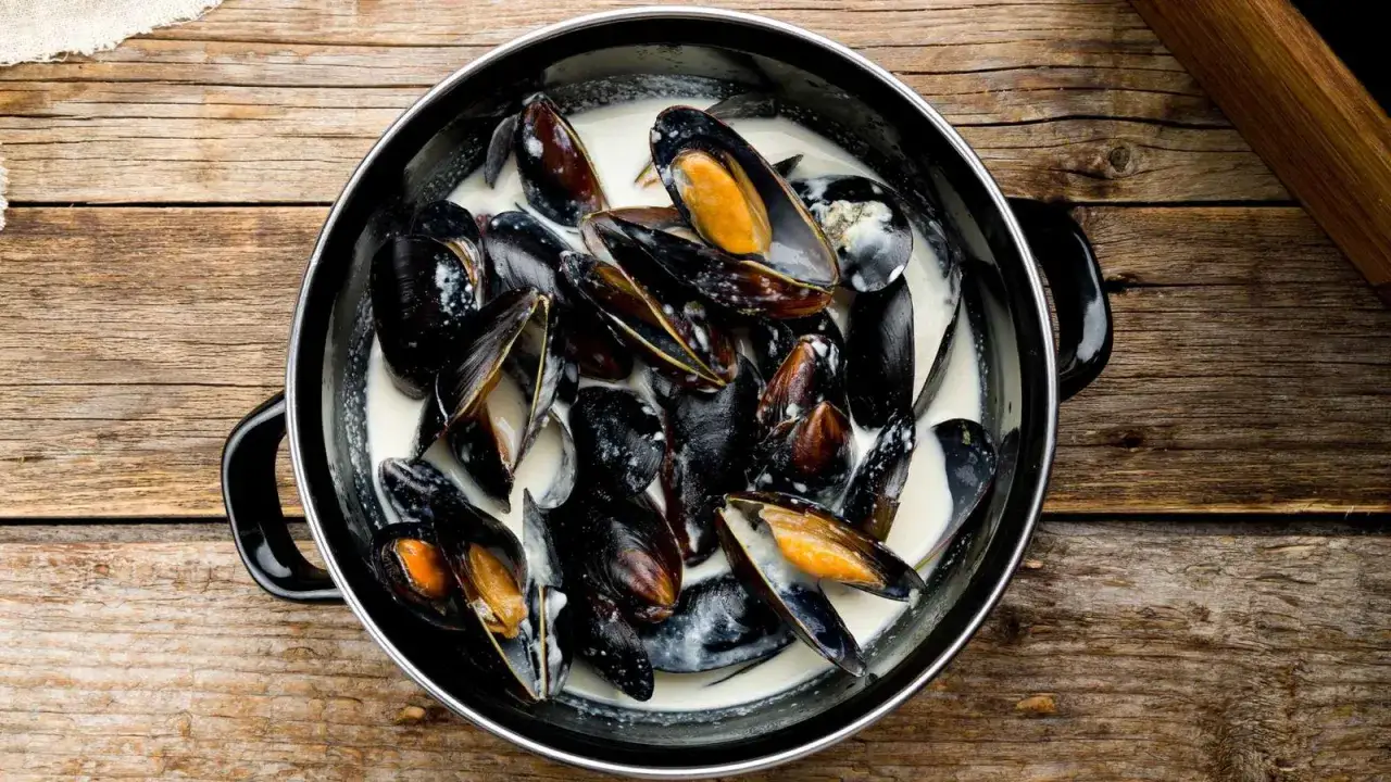 Un plat de moules &agrave; la cr&egrave;me, pr&ecirc;tes &agrave; &ecirc;tre d&eacute;gust&eacute;es sur une table en bois rustique.