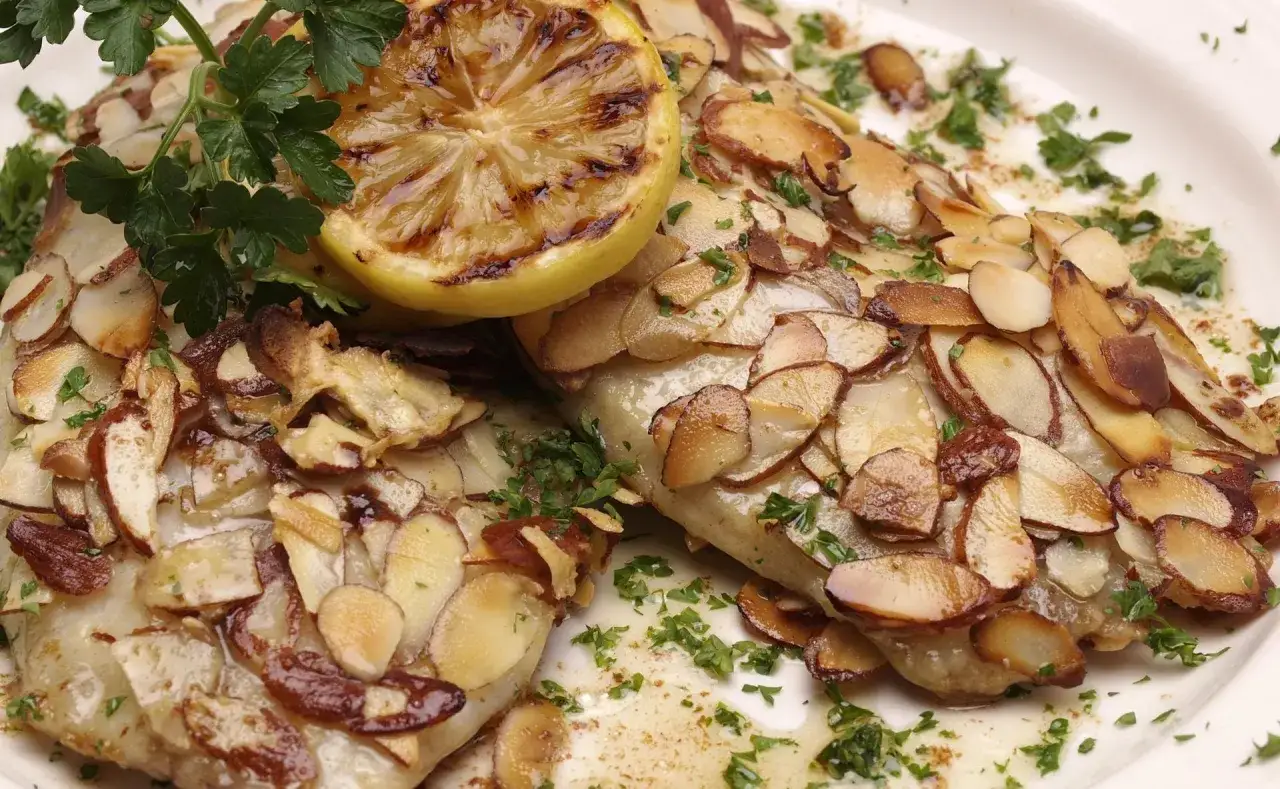 D&eacute;licieuse truite aux amandes au four, garnie d'une tranche de citron grill&eacute;e et de persil frais. Un plat savoureux et croustillant.