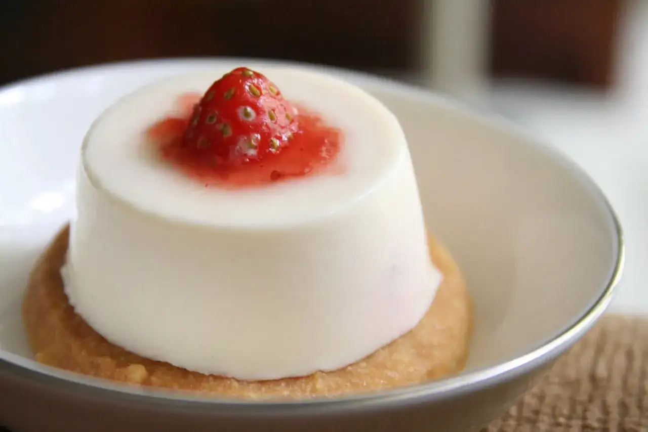 Panna cotta à la fraise sur un biscuit. Si elle est trop liquide, voici comment rattraper une panna cotta trop liquide pour un dessert parfait.