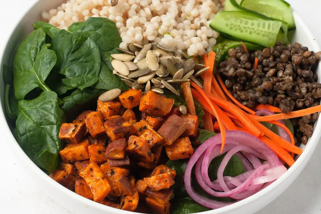 Un bol color&eacute; avec des d&eacute;s de patate douce r&ocirc;tie, des lentilles, des &eacute;pinards, des carottes r&acirc;p&eacute;es, des concombres et des graines. Parfait pour une recette de freekeh.