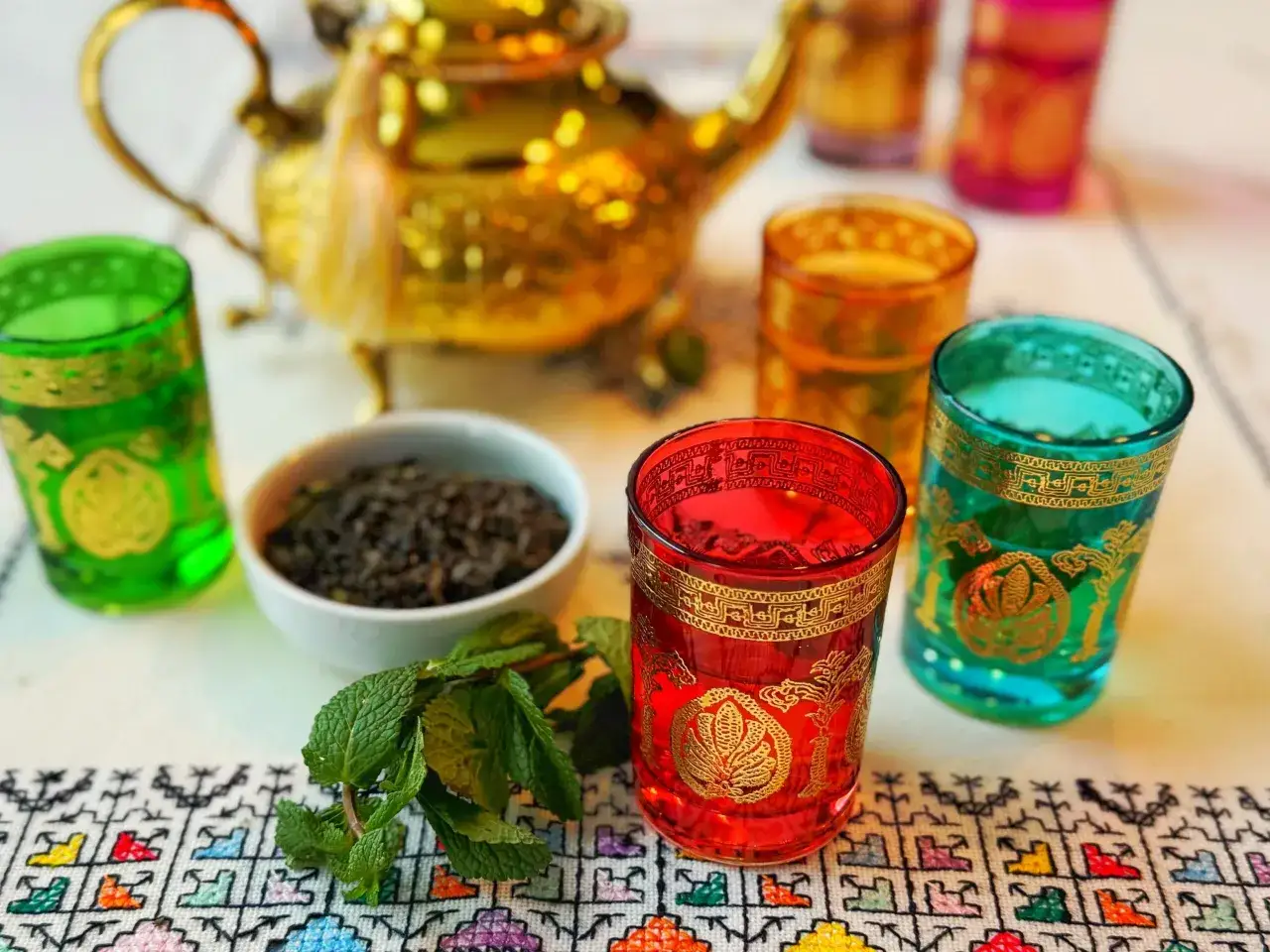 Th&eacute; &agrave; la menthe, un dessert marocain embl&eacute;matique, servi dans des verres color&eacute;s avec une th&eacute;i&egrave;re dor&eacute;e.