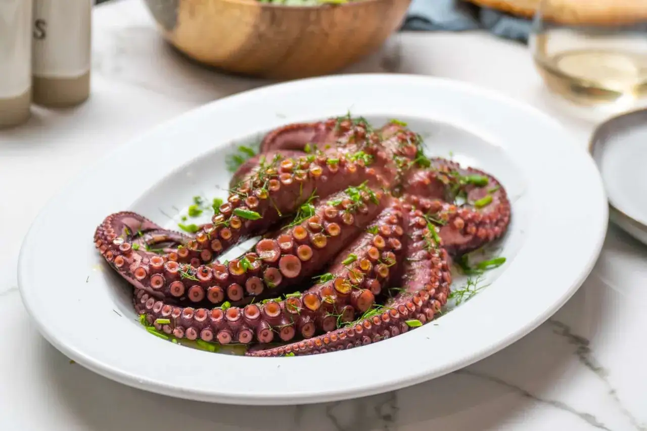Un poulpe entier, cuit et garni d'herbes fra&icirc;ches, pr&ecirc;t &agrave; &ecirc;tre d&eacute;gust&eacute;. Une recette de poulpe simple et savoureuse.