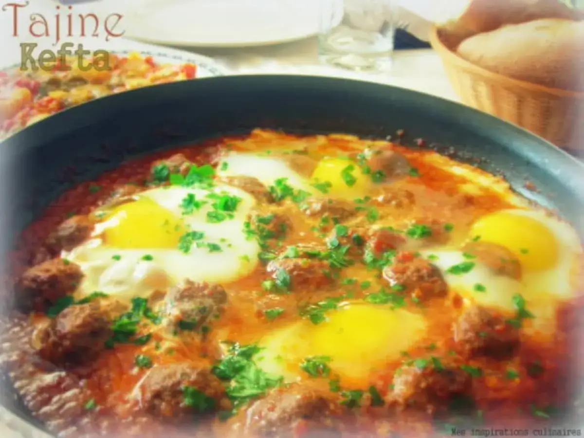 Un savoureux tajine kefta oeuf, garni de persil frais, mijote dans une sauce tomate &eacute;pic&eacute;e.