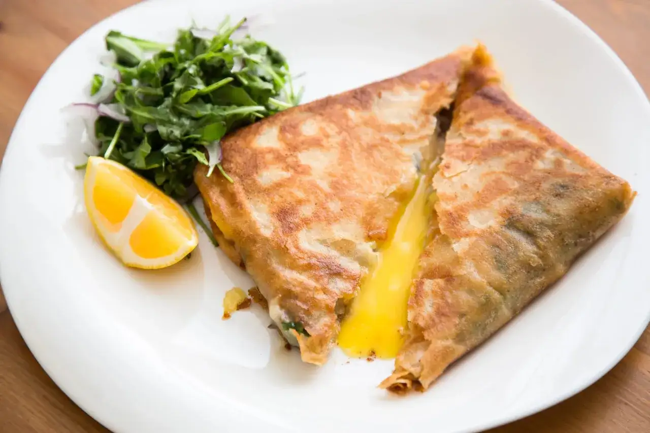 Un d&eacute;licieux brick au thon, dor&eacute; et croustillant, avec un c&oelig;ur coulant de fromage. Servi avec une salade verte et un quartier de citron.