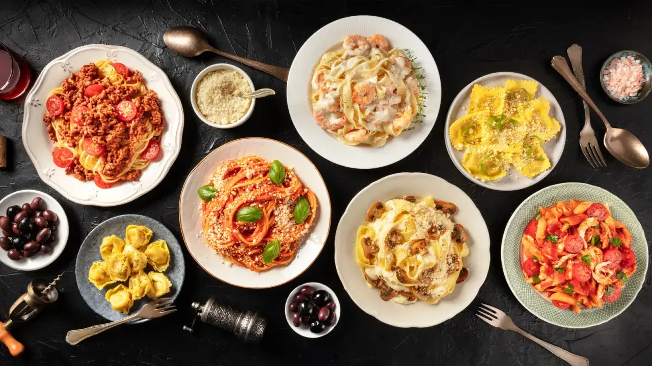 Un festin de p&acirc;tes vari&eacute;es : spaghetti &agrave; la bolognaise, fettuccine aux crevettes, raviolis, penne &agrave; la sauce tomate, et plus encore. Une belle table de p&acirc;tes types.