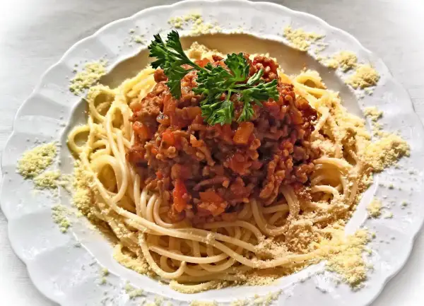 Une assiette de spaghetti bolognaise italienne, garnie de persil frais et de parmesan râpé. Un délice pour les amateurs de cuisine italienne.