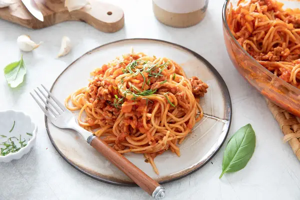 Une assiette de spaghetti à la bolognaise, plat réconfortant de one pot pasta, garnie d'herbes fraîches.