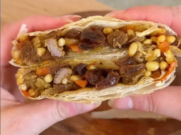 Une délicieuse pastilla agneau, coupée en deux, révèle sa garniture généreuse de viande, raisins secs, pignons et carottes.