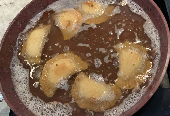 Des samboussek au fromage dorent dans l'huile chaude, formant des bulles joyeuses.