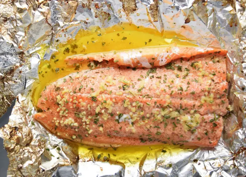 Filet de truite cuit en papillote, assaisonné d'ail et d'herbes, baignant dans un jus doré. Une recette simple et savoureuse.